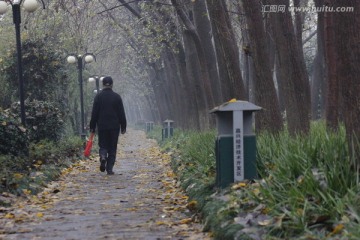 行走在阴雨天绿道上的老人