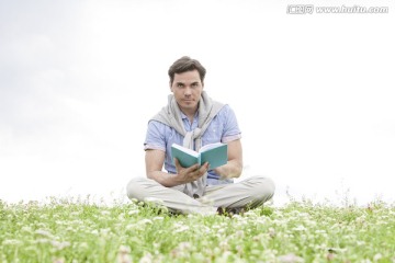 坐在草地上的年轻人看书
