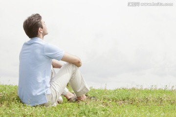 年轻人坐在草地上看天
