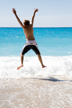 海边跳跃的小男孩