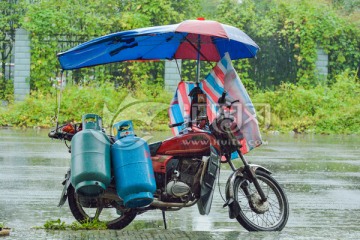 雨中送煤气罐的摩托车