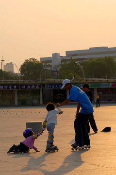 夕阳斜照 练习旱冰的儿童和教练