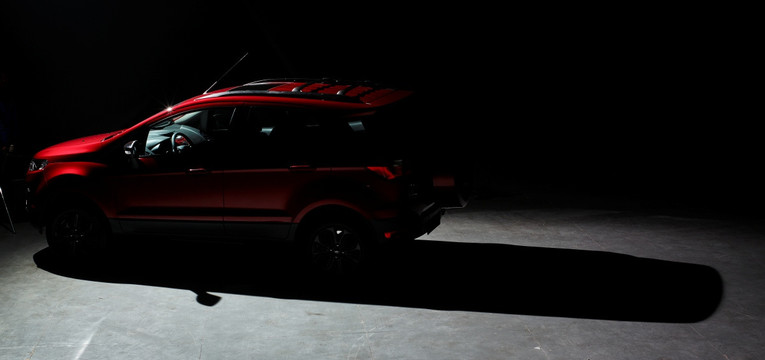 黑背景展台上的红色SUV的侧翼