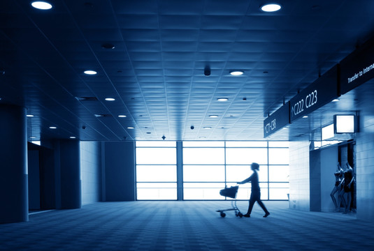 机场航站楼里推行李车的旅客
