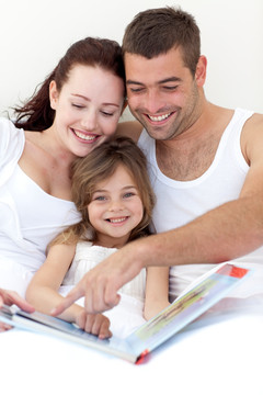 父母和女儿在床上看书