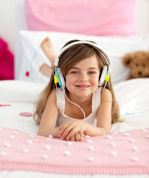 微笑的女孩在床上听音乐