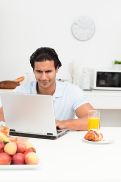 早餐时使用笔记本电脑的男人