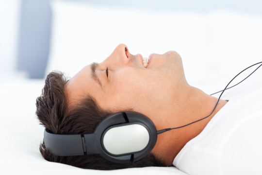 躺在床上听音乐的男性