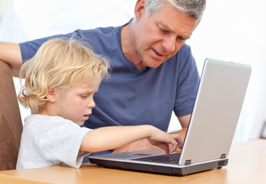 小男孩和祖父一起玩笔记本电脑