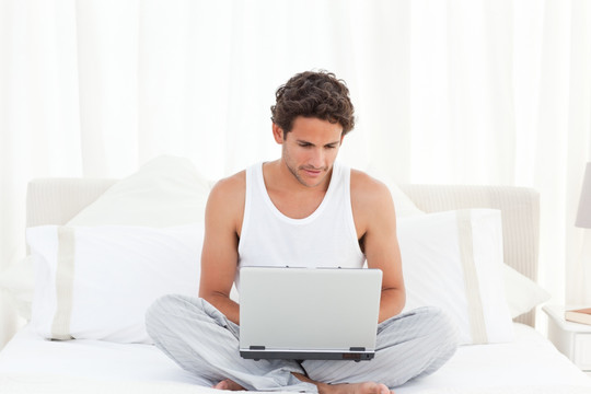 在床上使用笔记本电脑工作的男人