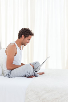 在床上使用笔记本电脑工作的男人