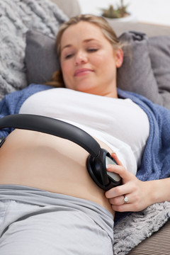 孕妇把耳机放在腹部