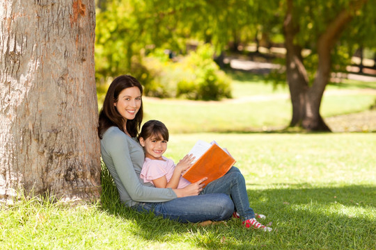 女儿和妈妈在树下看相册