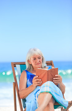 在海滩上看书的老妇人