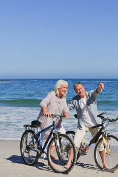 在海边骑自行车的老年夫妇