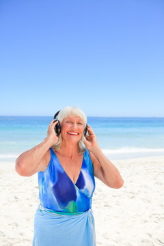 在海边听音乐的老年妇女