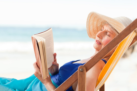 老年妇女在海滩上阅读