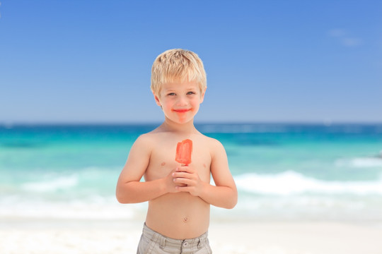 小男孩在海滩上吃棒冰