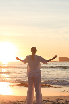 日落时在海边练习瑜伽的女人
