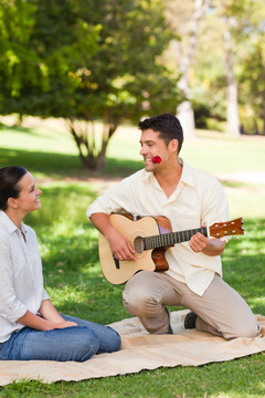在公园里弹吉他给女朋友听的男人