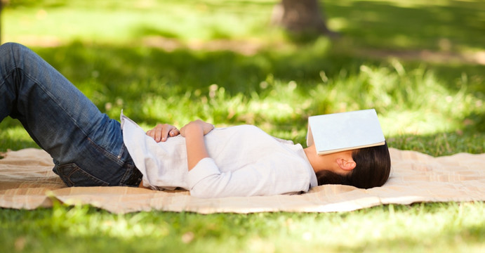 躺在毯子上用书蒙着脸的女人