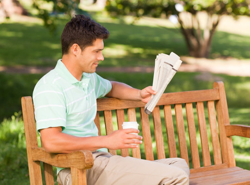 坐在公园长椅看报纸的男人