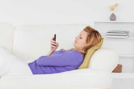 躺在沙发上玩手机的金发女人