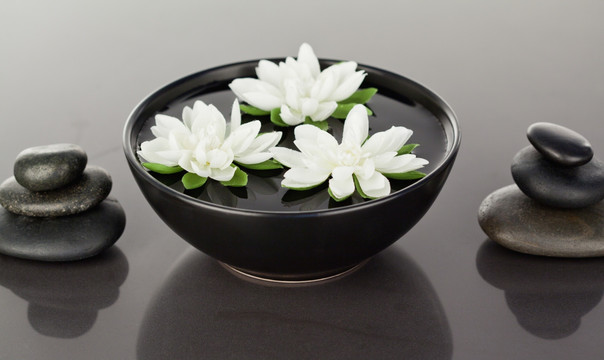 白莲花漂浮在包围着鹅卵石的碗里
