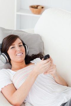 躺在沙发上听音乐玩手机的女人