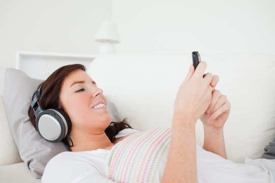 躺在沙发上听音乐玩手机的女人