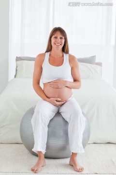 微笑的孕妇坐在健身球上