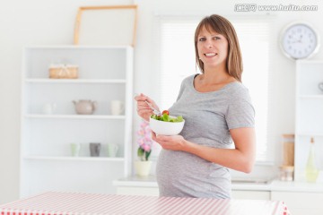 在厨房吃水果沙拉的孕妇