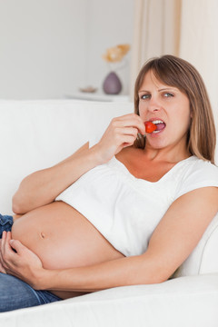 躺在沙发上吃草莓的孕妇