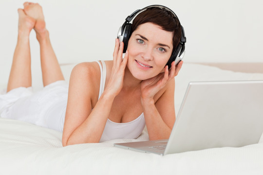 在床上使用电脑听音乐的女人