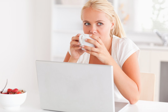 女人在电脑前喝着咖啡