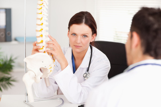 女医生给她的病人展示脊椎骨