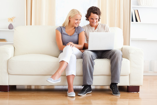 年轻的夫妇在沙发上使用平板电脑