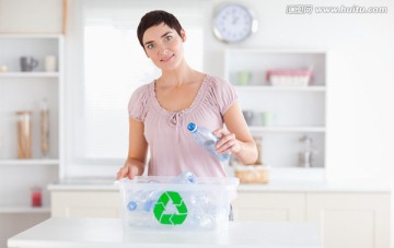 美丽的女人把塑料瓶放进回收箱
