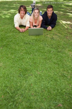 趴在草地上使用电脑的大学同学