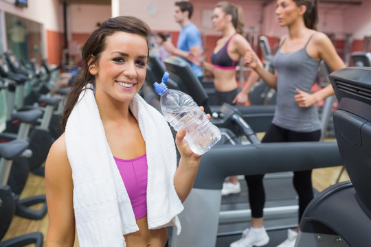 年轻女人在跑步机前喝水
