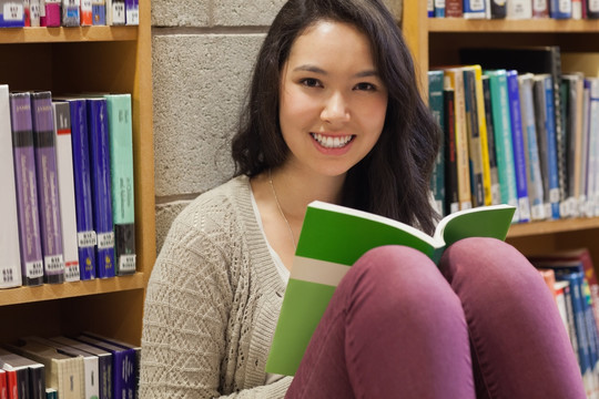 女学生做在图书馆地板上看书