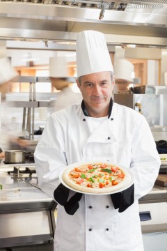 厨师长拿着一盘披萨