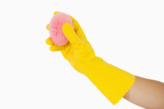 戴着黄色手套的手拿着海绵