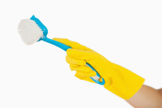 戴着黄色手套的手拿着洗涤刷