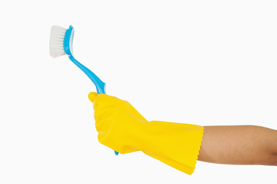 戴着黄色手套的手拿着擦洗刷