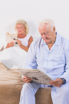 在卧室读书看报的老年夫妇