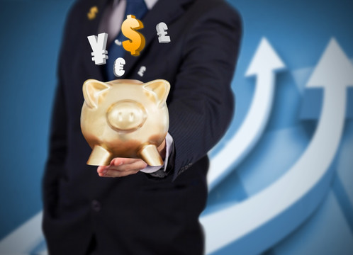 西裝男性手持金豬存錢罐