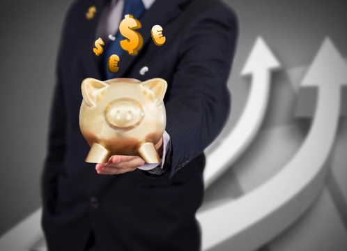 西裝男性手持金豬存錢罐