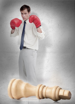 戴著拳擊手套的男人和撞倒的棋子
