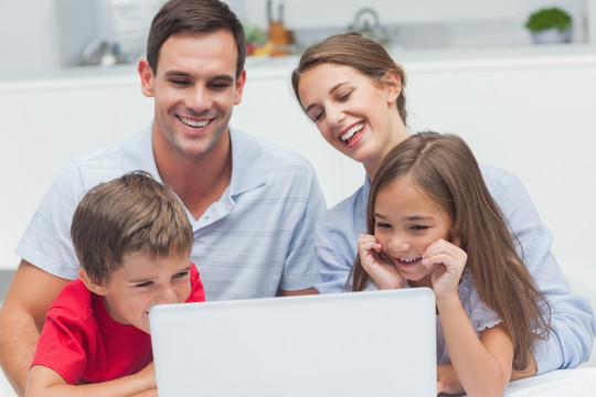 一家人微笑着看着笔记本电脑